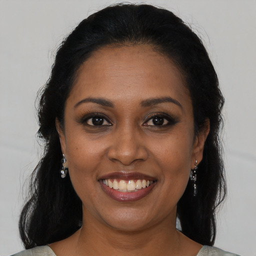 Joyful black young-adult female with long  brown hair and brown eyes