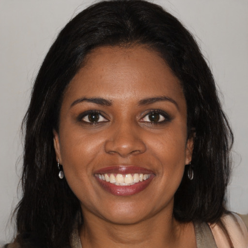 Joyful black young-adult female with long  brown hair and brown eyes