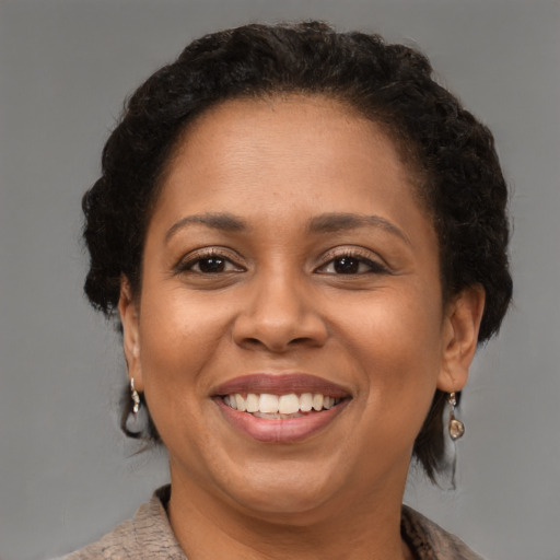 Joyful black adult female with medium  brown hair and brown eyes