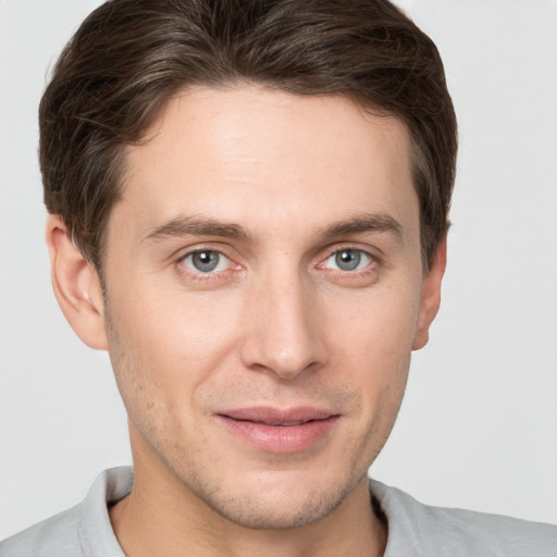 Joyful white young-adult male with short  brown hair and grey eyes