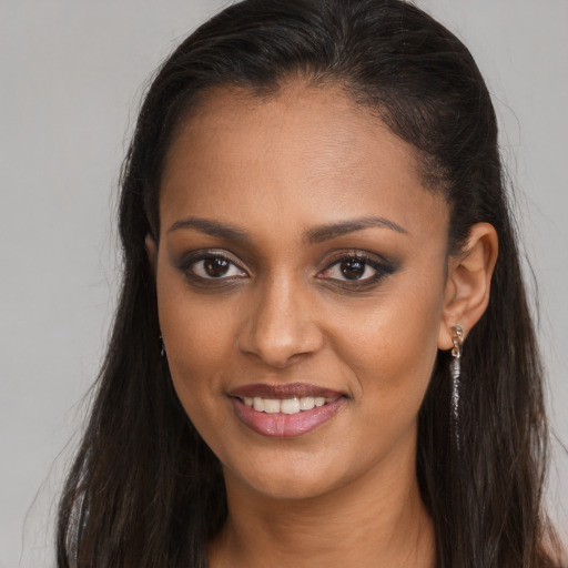 Joyful black young-adult female with long  brown hair and brown eyes