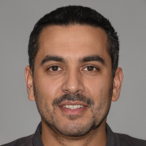 Joyful white adult male with short  black hair and brown eyes