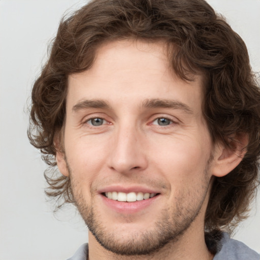 Joyful white young-adult male with medium  brown hair and grey eyes