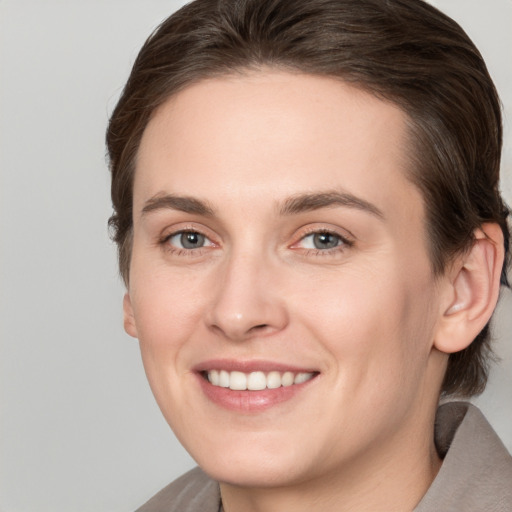 Joyful white young-adult female with medium  brown hair and grey eyes