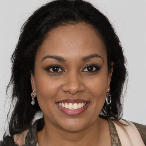 Joyful black young-adult female with long  brown hair and brown eyes