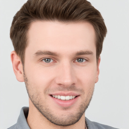 Joyful white young-adult male with short  brown hair and grey eyes