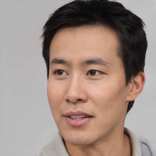 Joyful asian adult male with short  brown hair and brown eyes