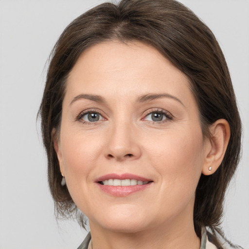 Joyful white young-adult female with medium  brown hair and grey eyes