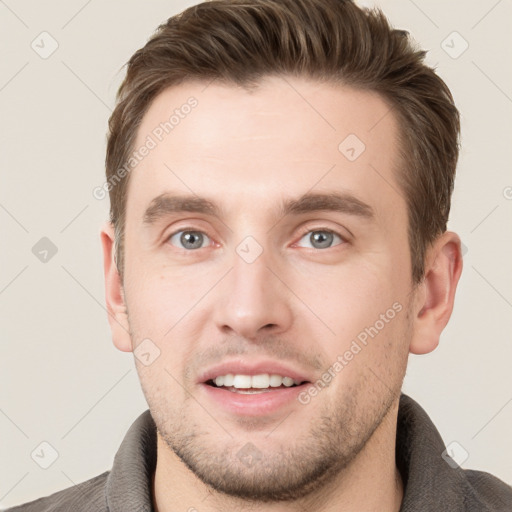 Joyful white young-adult male with short  brown hair and grey eyes