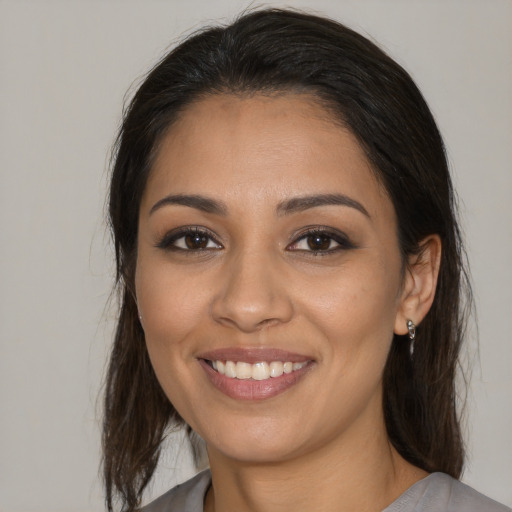 Joyful latino young-adult female with medium  brown hair and brown eyes