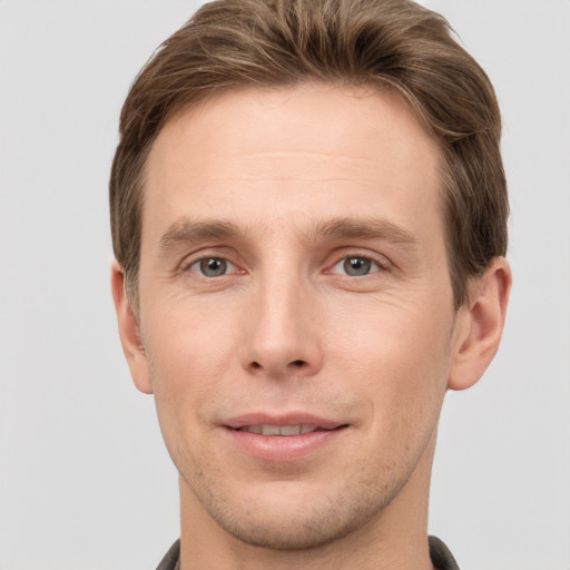 Joyful white young-adult male with short  brown hair and grey eyes