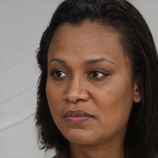 Joyful black adult female with long  brown hair and brown eyes