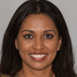 Joyful black young-adult female with long  brown hair and brown eyes