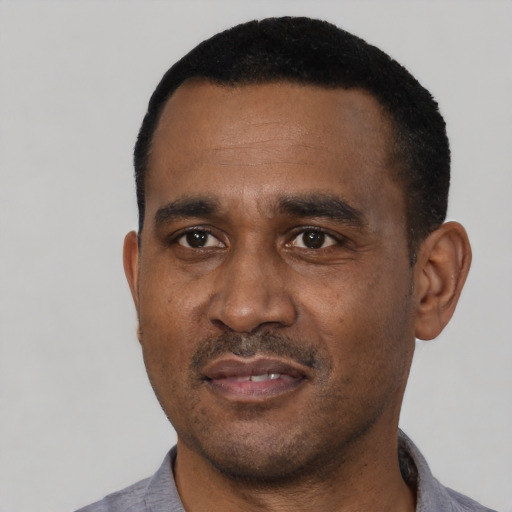 Joyful black adult male with short  black hair and brown eyes