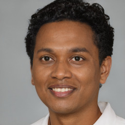 Joyful black young-adult male with short  black hair and brown eyes