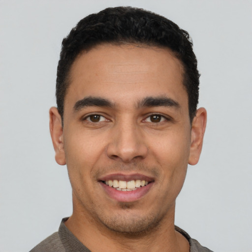 Joyful latino young-adult male with short  black hair and brown eyes