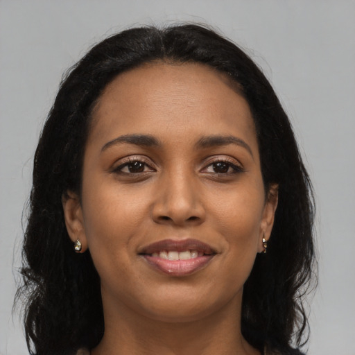 Joyful black young-adult female with long  black hair and brown eyes