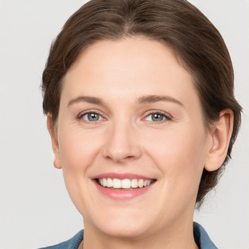 Joyful white young-adult female with medium  brown hair and grey eyes