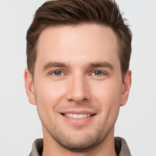 Joyful white young-adult male with short  brown hair and grey eyes