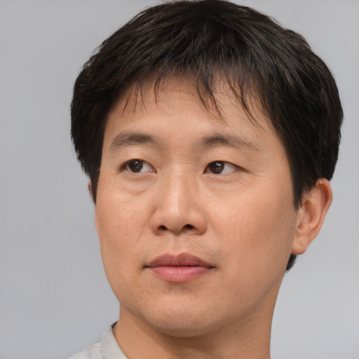 Joyful asian young-adult male with short  brown hair and brown eyes