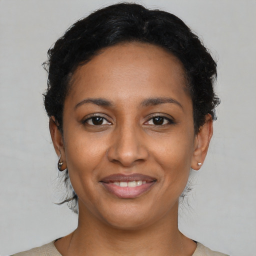 Joyful black young-adult female with short  black hair and brown eyes