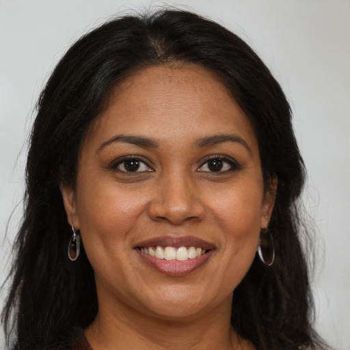 Joyful black adult female with long  brown hair and brown eyes