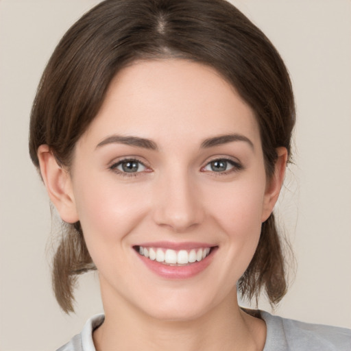 Joyful white young-adult female with medium  brown hair and grey eyes