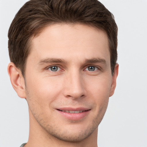 Joyful white young-adult male with short  brown hair and grey eyes