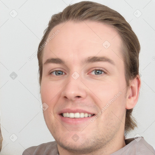 Joyful white young-adult male with short  brown hair and grey eyes