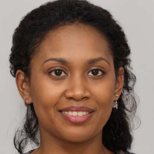Joyful black young-adult female with long  brown hair and brown eyes