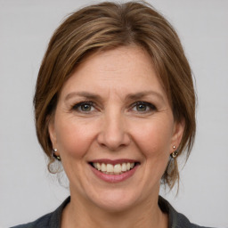 Joyful white adult female with medium  brown hair and grey eyes