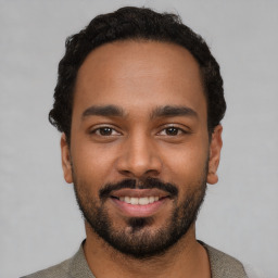 Joyful black young-adult male with short  black hair and brown eyes