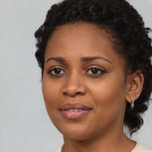 Joyful black young-adult female with short  black hair and brown eyes