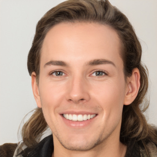 Joyful white young-adult male with long  brown hair and brown eyes