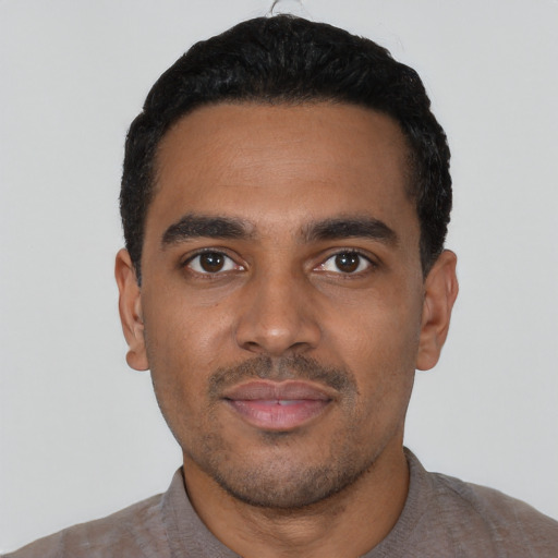 Joyful black young-adult male with short  black hair and brown eyes