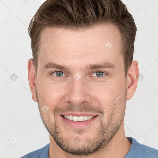 Joyful white young-adult male with short  brown hair and grey eyes