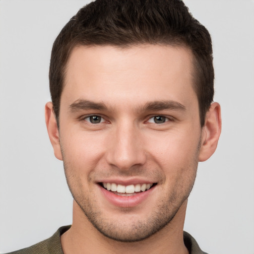 Joyful white young-adult male with short  brown hair and grey eyes