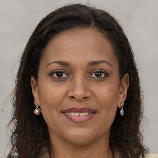 Joyful black young-adult female with long  brown hair and brown eyes