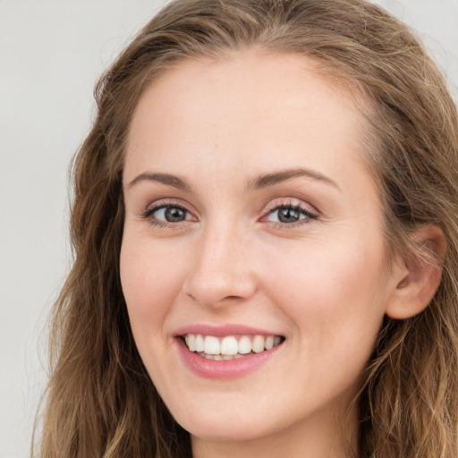 Joyful white young-adult female with long  brown hair and blue eyes