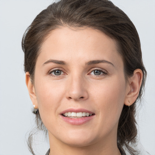 Joyful white young-adult female with medium  brown hair and grey eyes