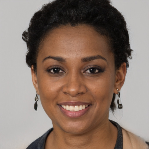 Joyful black young-adult female with short  black hair and brown eyes