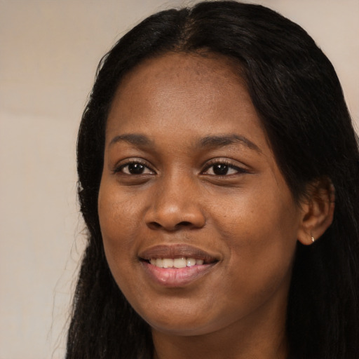 Joyful black young-adult female with long  black hair and brown eyes