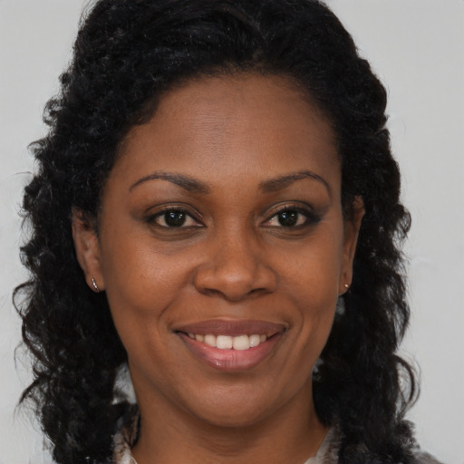 Joyful black adult female with long  brown hair and brown eyes