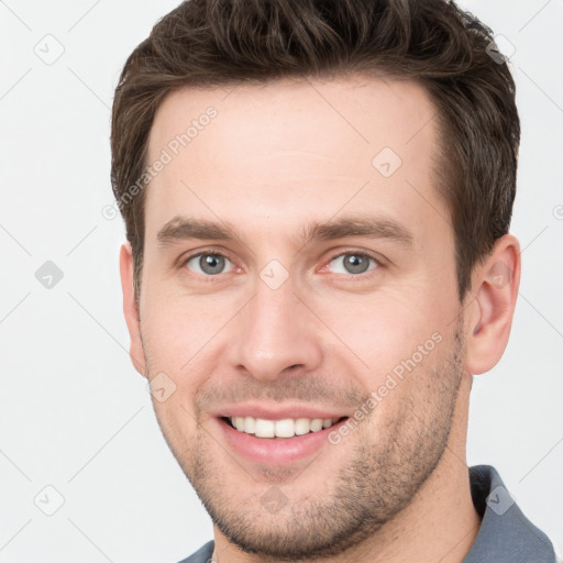 Joyful white young-adult male with short  brown hair and grey eyes