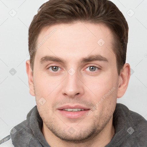 Joyful white young-adult male with short  brown hair and grey eyes