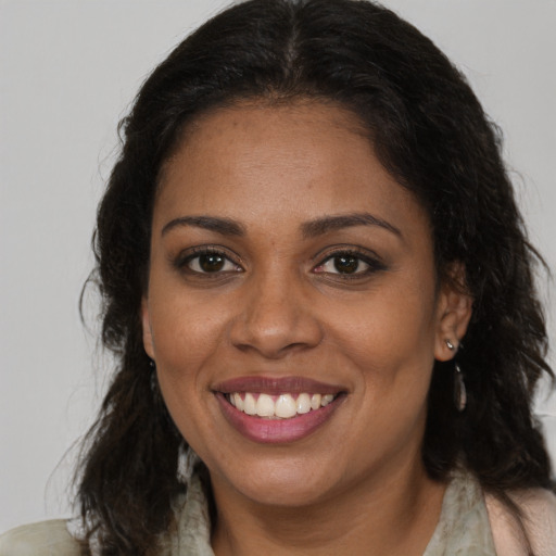 Joyful black young-adult female with long  brown hair and brown eyes