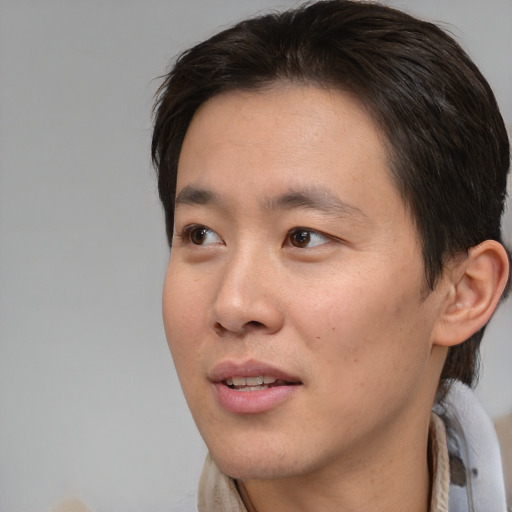 Joyful asian young-adult male with short  brown hair and brown eyes