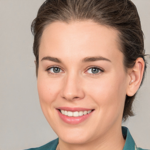 Joyful white young-adult female with medium  brown hair and grey eyes