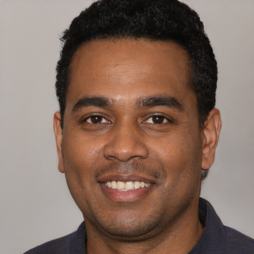 Joyful black young-adult male with short  black hair and brown eyes