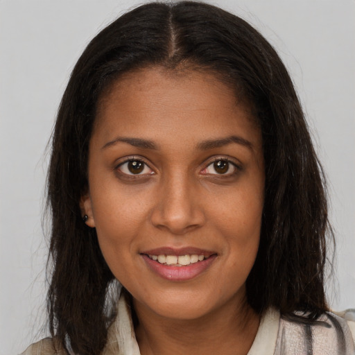 Joyful black young-adult female with long  brown hair and brown eyes